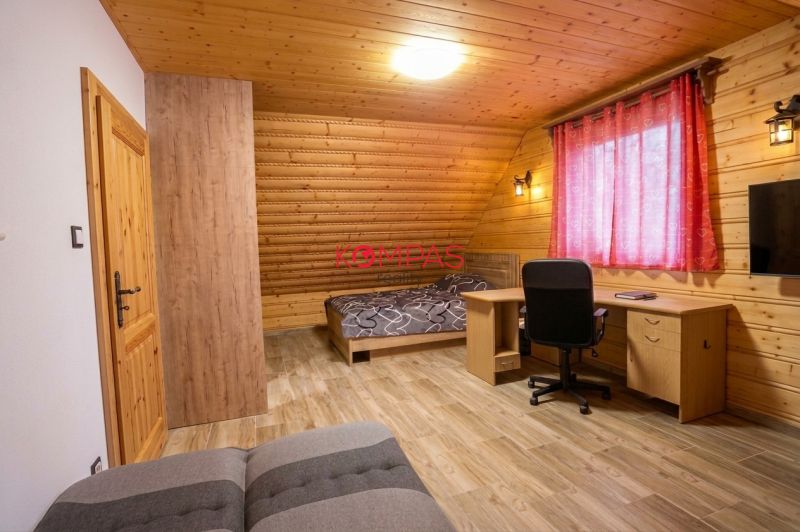 A room in a family house with wooden walls, a floor with a wooden decor, and a work desk.