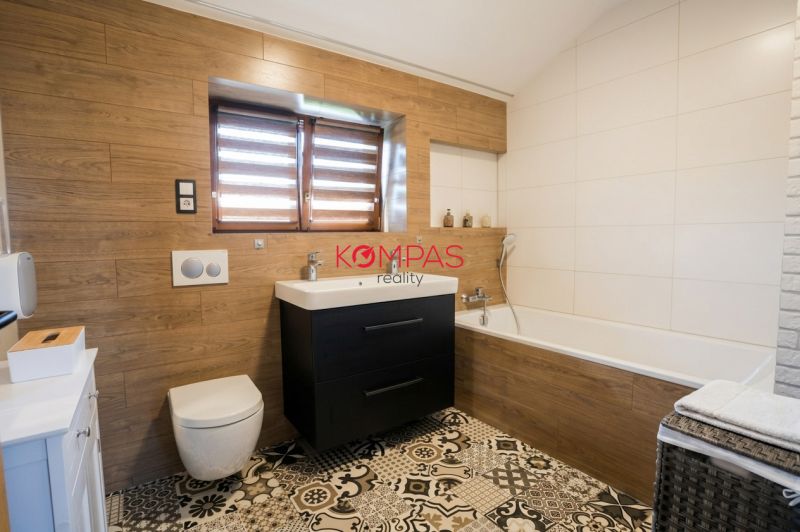 A bathroom in a family house with a bathtub, a sink, and a floor with a wooden decor.