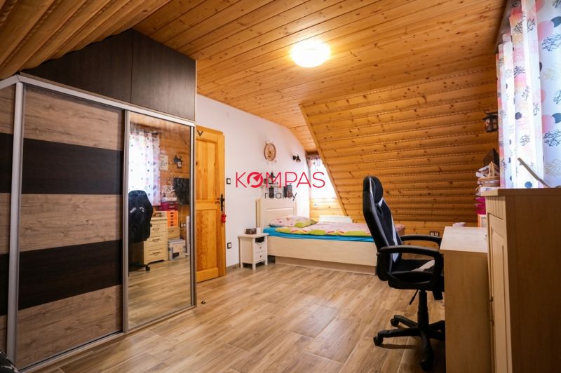 Attic room with wooden ceiling paneling, bed, wardrobe, and floor with wooden decor.