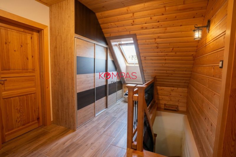 Attic hallway with wooden paneling and wood-decor flooring in a family house.
