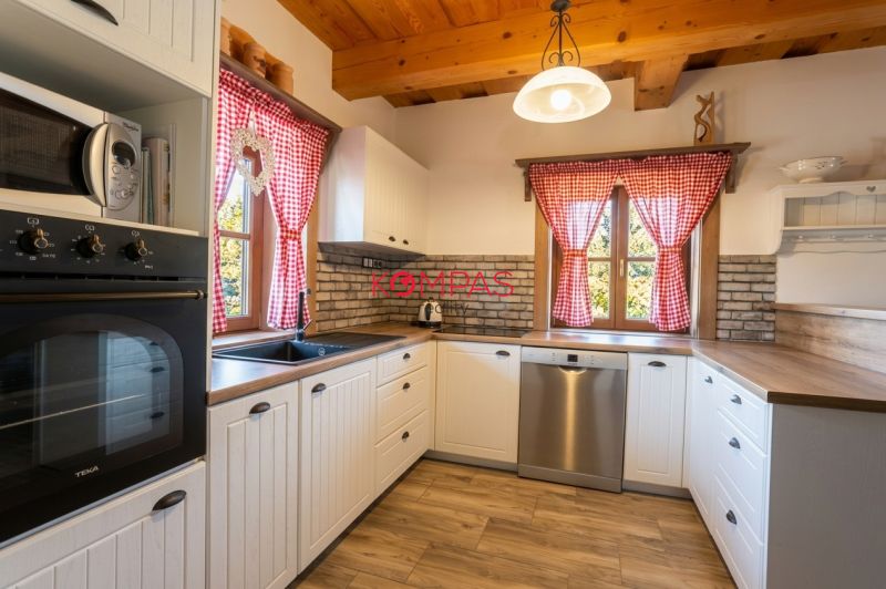 A kitchen unit in a family house with red curtains and a wooden decor floor.