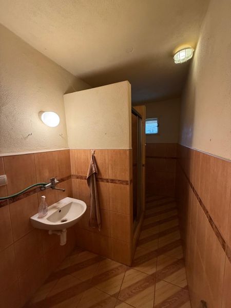 A bathroom in a family house with a wooden decor floor and a shower corner.