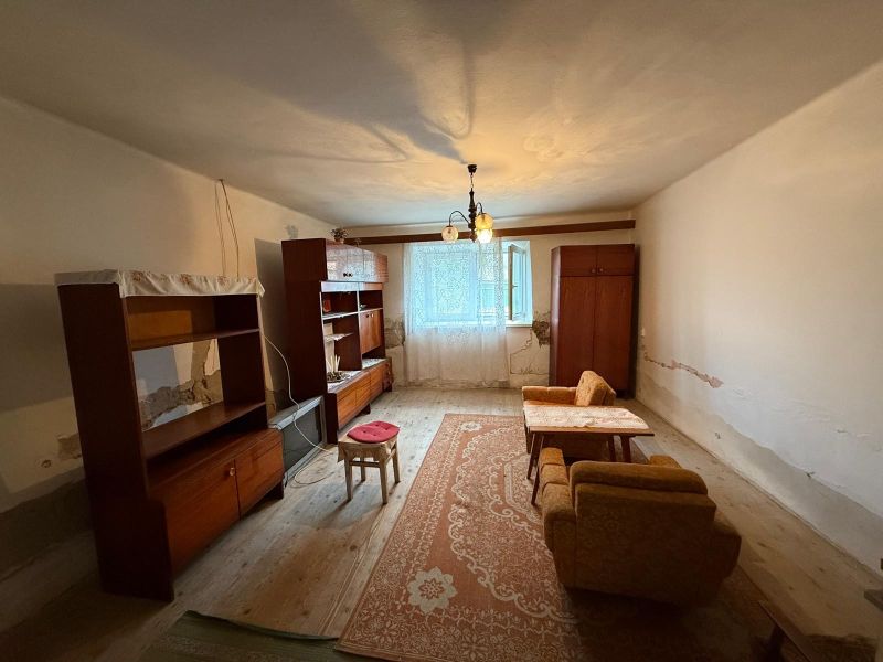 A room in a family house with furniture on a wooden-decor floor and a carpet.