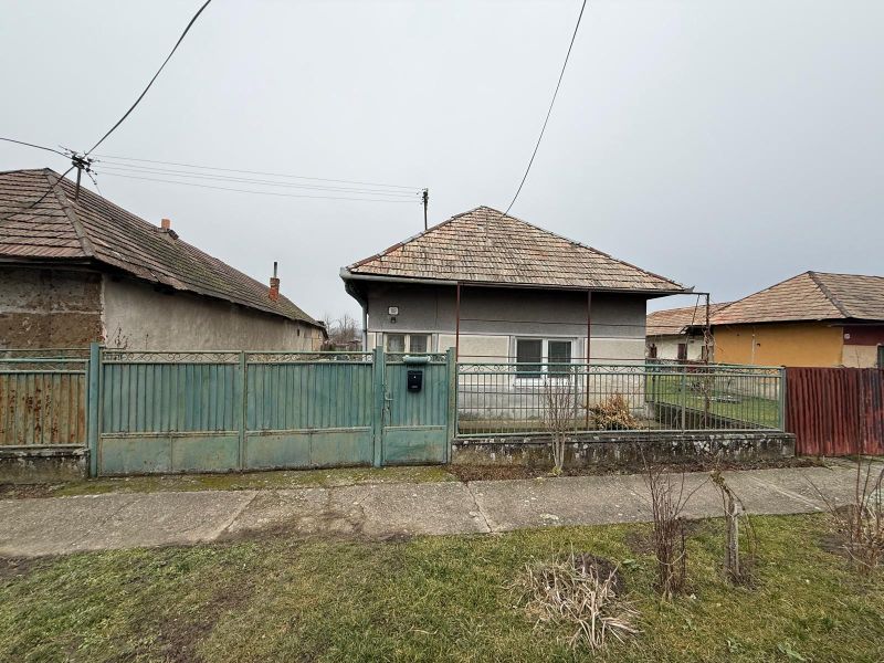 A family house in Sikenica with a metal fence and a sloped roof.