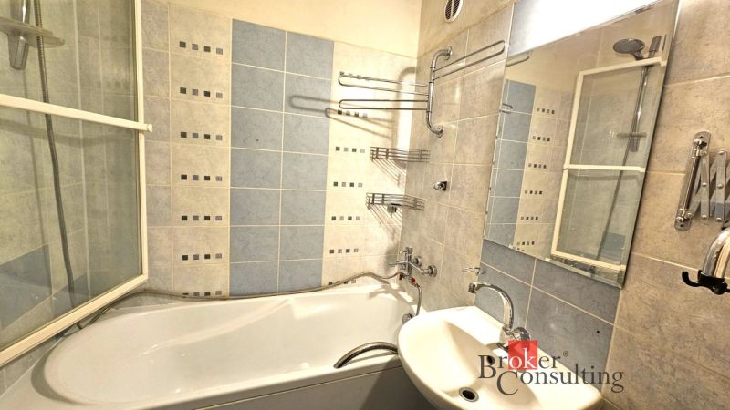 A bathroom in a 4-room apartment with a bathtub, sink, and blue tiles.