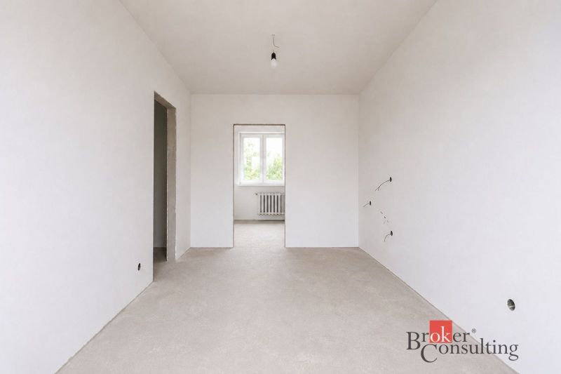 Empty room in a 4-room apartment with white walls and a window.