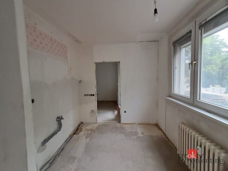 Room in a 4-room apartment with white walls and a large window.