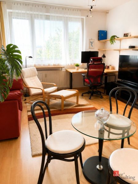 Living room in a two-room apartment with a wooden decor floor and a work corner.