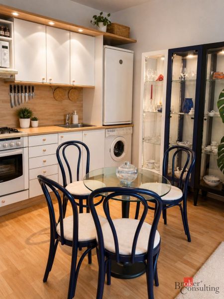 A kitchen in a 2-room apartment with a wooden decor floor and a dining table.