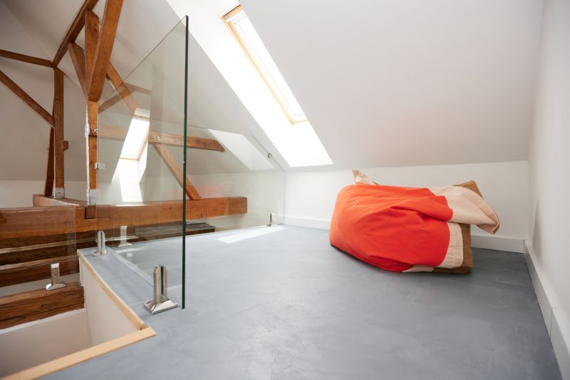 An attic space with glass railings and a colorful bean bag in a three-room apartment.