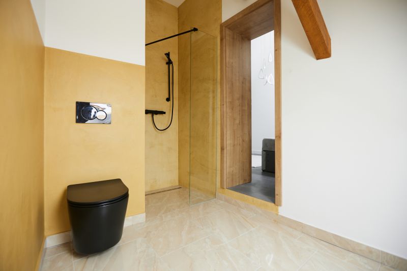 A bathroom with yellow walls, a black toilet, and a shower in a 3-room apartment.