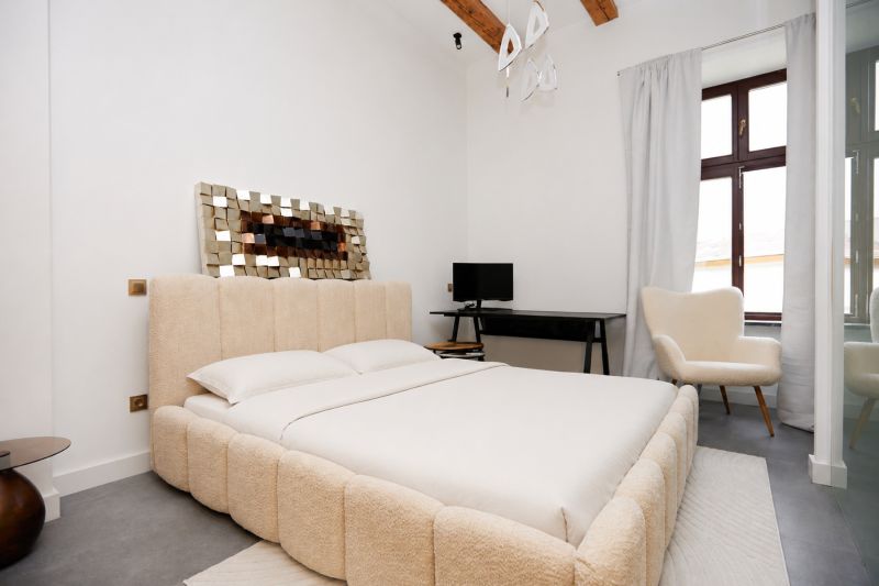 A bright bedroom with a comfortable bed, a desk, and a chair in a three-room apartment.