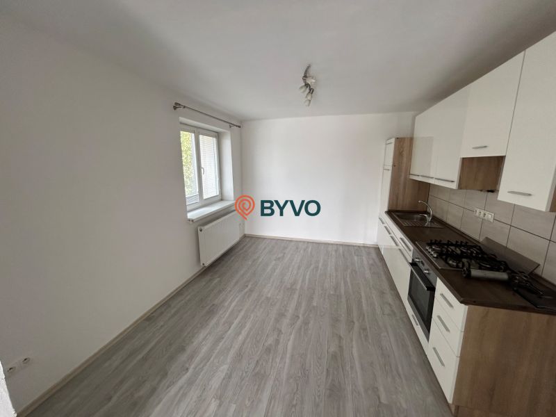 A kitchen with a white unit in a 3-room apartment, a floor with a wooden decor, a large window.