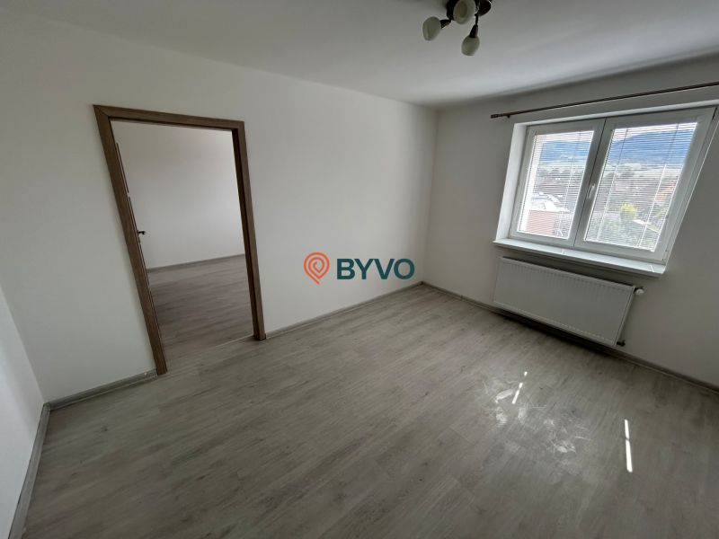 A room with a wooden floor decor, white walls, and a large window in a 3-room apartment.