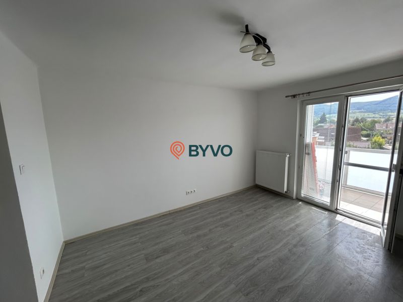 A room with a wooden decor floor and a balcony in a 3-room apartment.