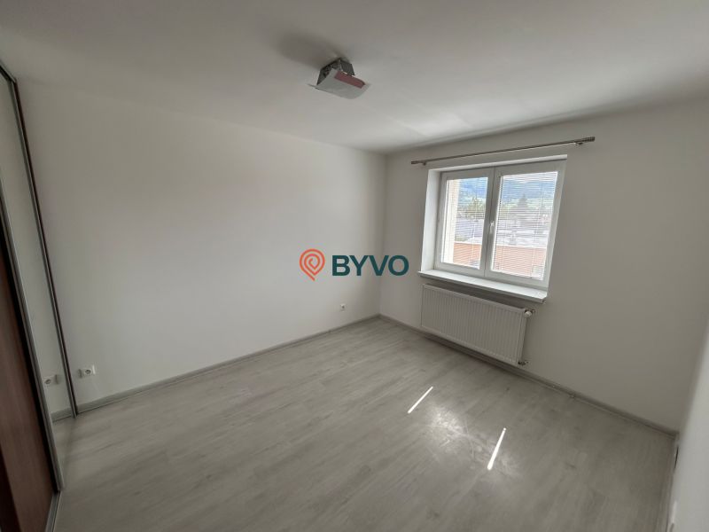 An empty room with wood-patterned flooring and white walls in a 3-room apartment.