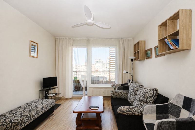 Living room with wood-patterned flooring and patterned furniture in a two-room apartment.