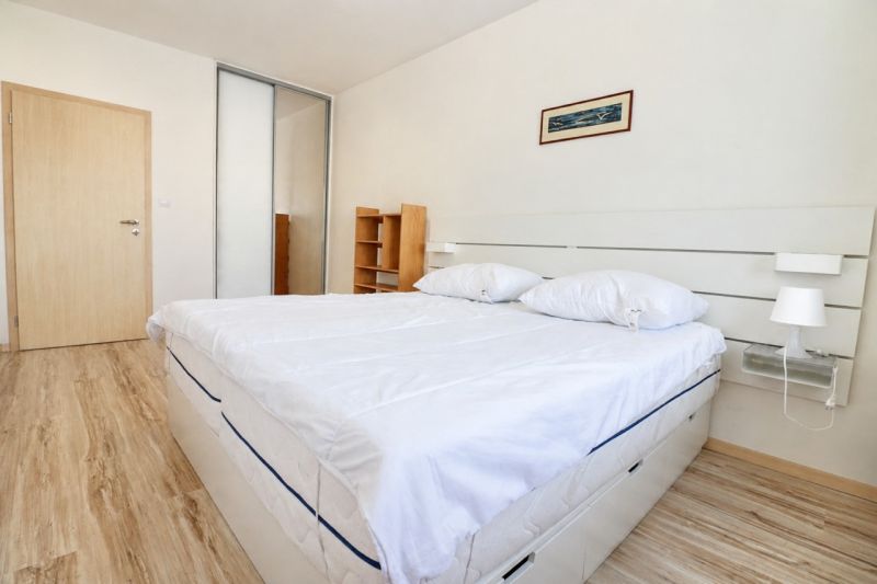 A bedroom with a wood-patterned floor, a large bed, and a built-in wardrobe in a 2-room apartment.