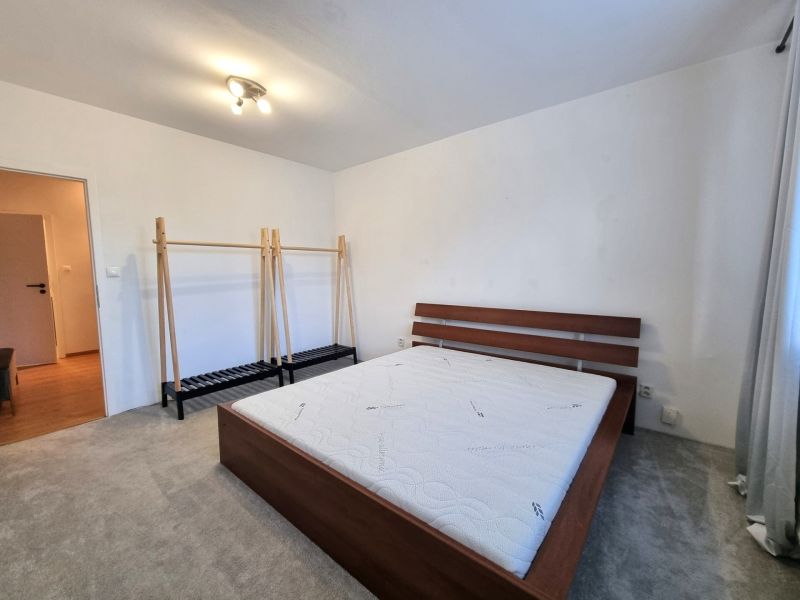 A bedroom with a bed and a hanger in a 2-room apartment, a floor with a wooden decor.