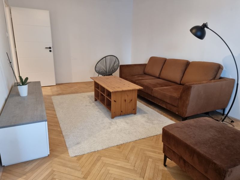 Living room in a two-room apartment, brown sofa, coffee table, wooden decor flooring.