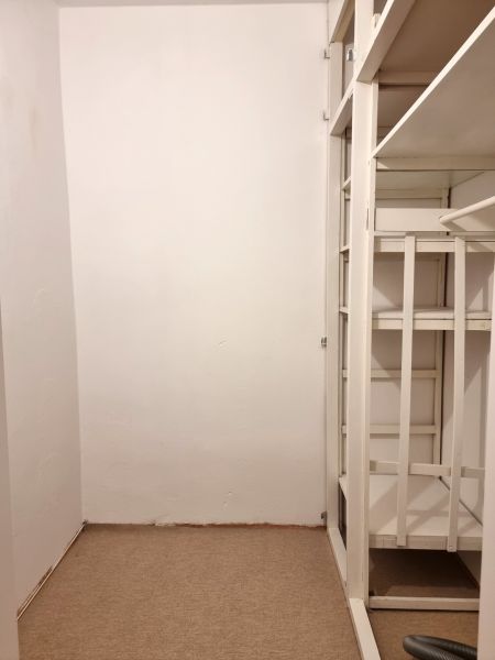 Storage space with white shelves in a 2-room apartment, with carpeted flooring.