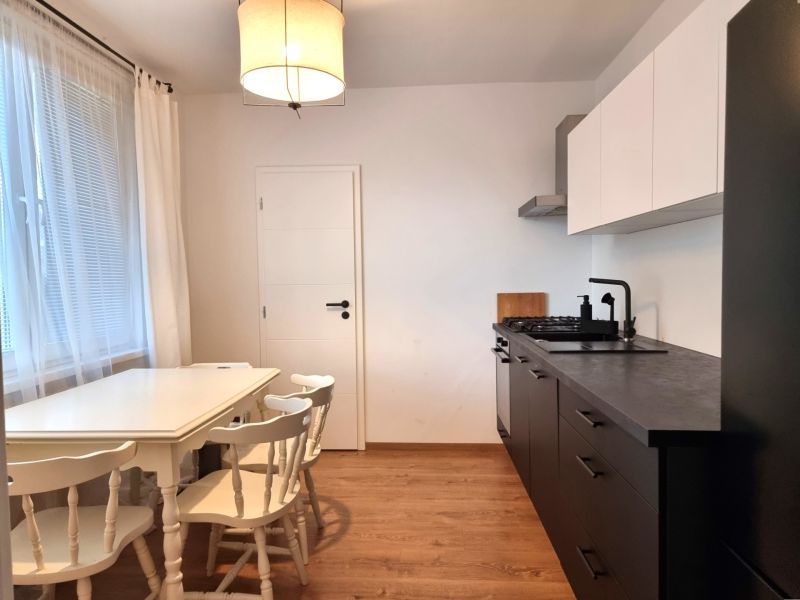 A kitchen in a 2-room apartment with a dining area and a wooden decor floor.