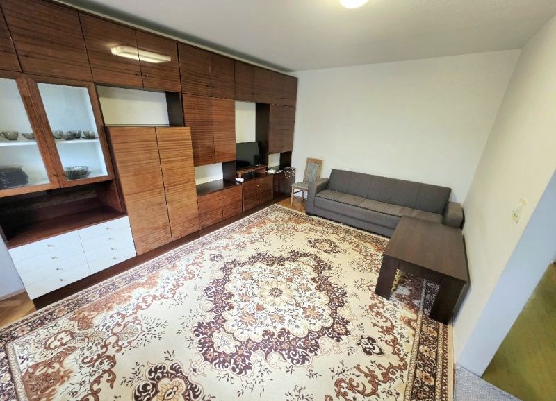 Living room in a 3-room apartment with furniture and a carpet on a floor with a wooden decor.