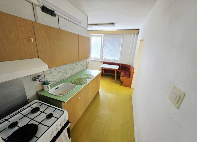 A kitchen in a 3-room apartment with simple equipment, wooden cabinets, and a dining area.