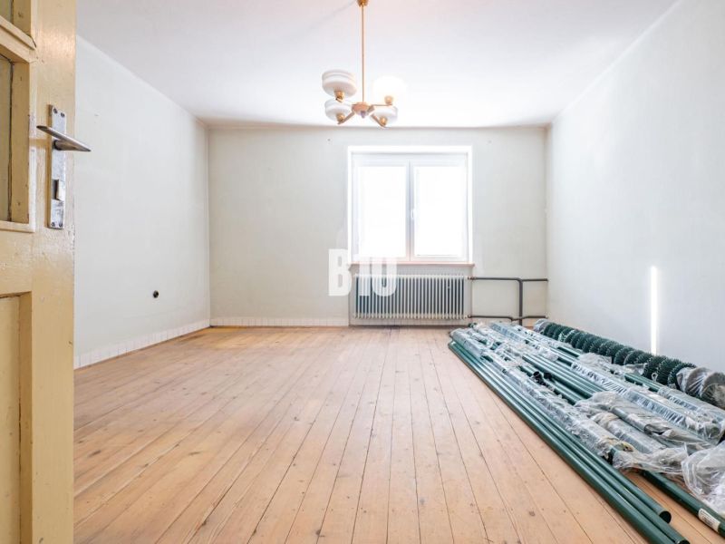 A room in a family house with a wooden decor floor and a pile of sticks by the window.