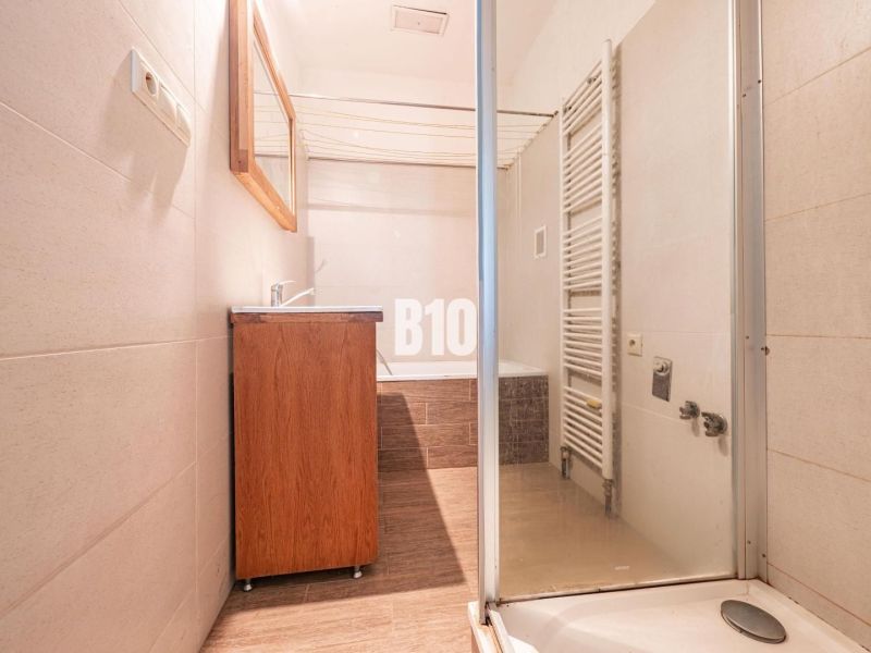 A bathroom in a family house with a shower, a sink, and a radiator, floor with a wooden decor.