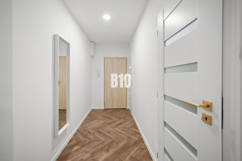 Hallway of a 3-room apartment with a wooden decor floor and a mirror on the wall.