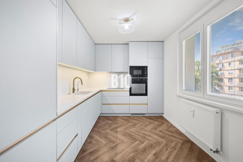 A kitchen with modern equipment and a wooden decor floor in a 3-room apartment.