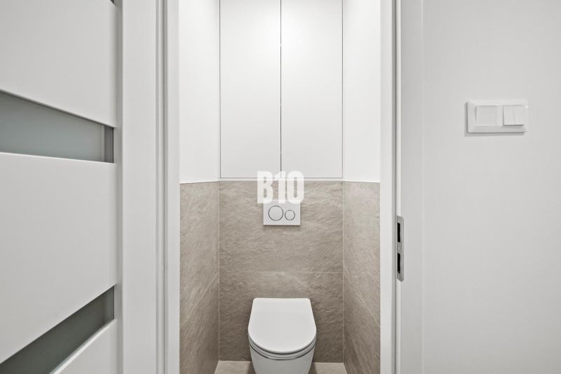 A toilet with white doors and tiles in a 3-room apartment.