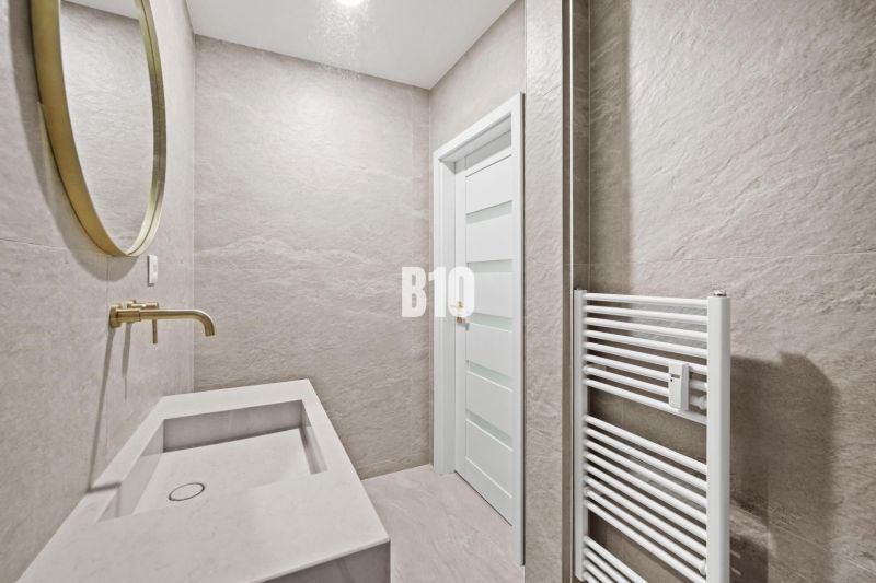 A bathroom with a gold mirror and sink in a 3-room apartment, neutral shades.