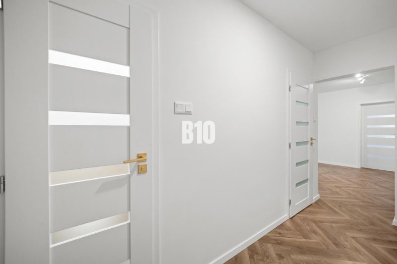 White interior of a 3-room apartment with wood-patterned flooring and elegant doors.