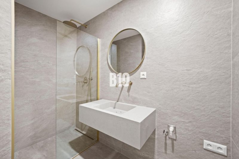 A bathroom with a round mirror and a shower in a 3-room apartment.