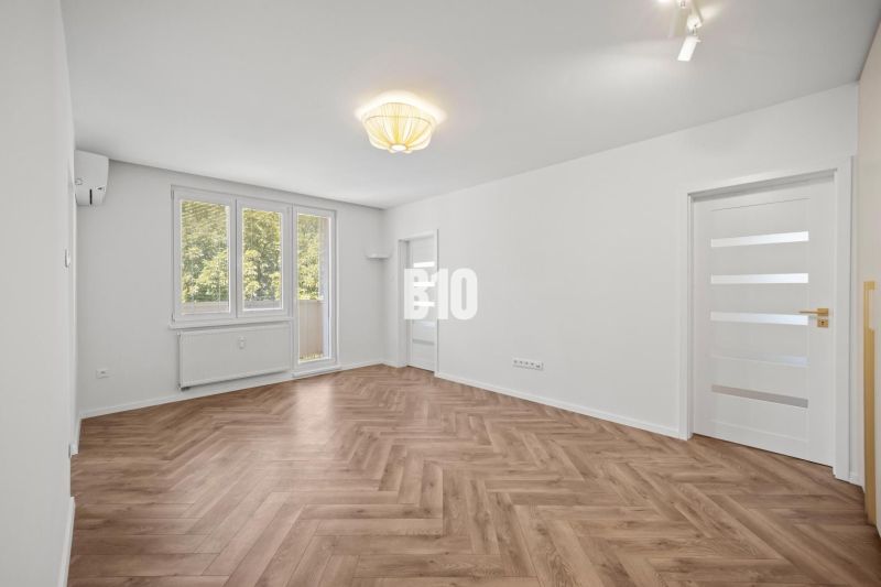 A spacious room with a wooden decor floor in a 3-room apartment.