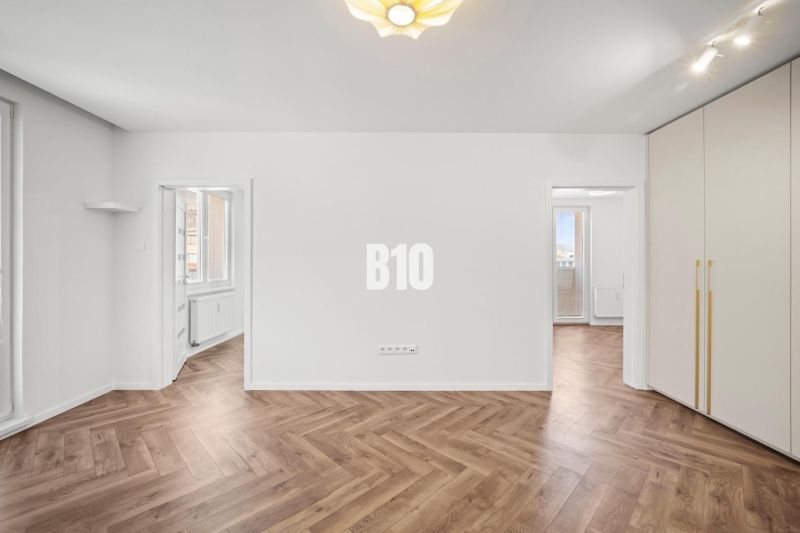 A room in a 3-room apartment with a wooden decor floor and built-in wardrobes.