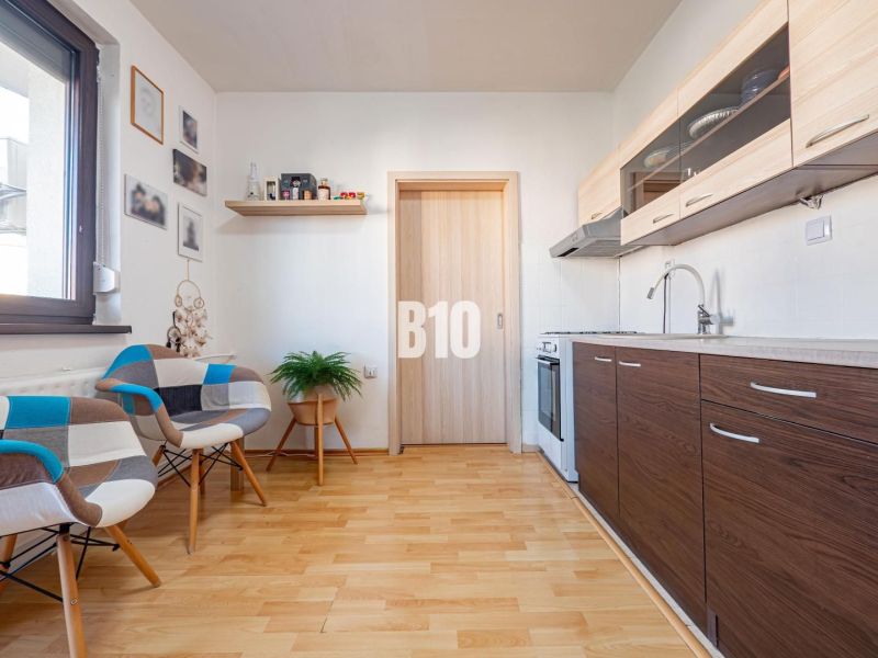 A kitchen in a one-room apartment with a wooden decor floor and modern furniture.