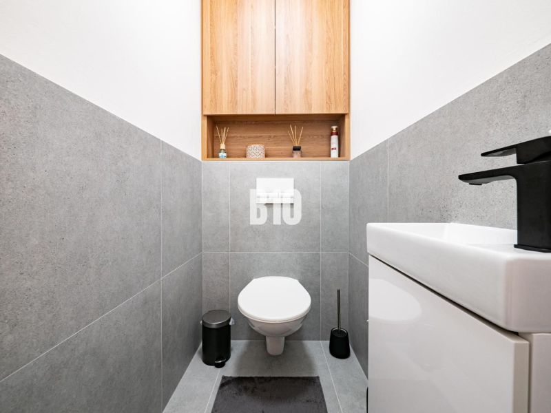A bathroom in a family house with gray tiles and a simple design.