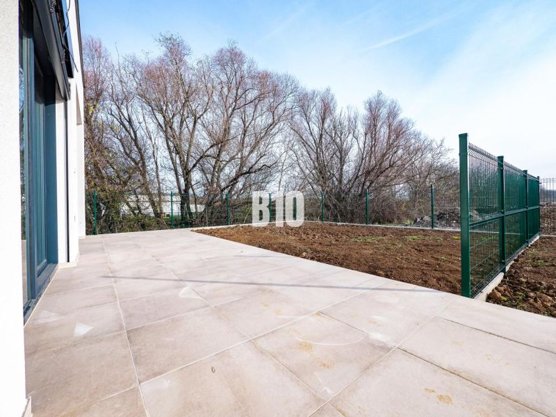 A terrace of a family house in Nitra with a tiled floor and a fenced garden.