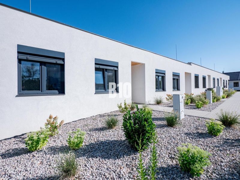 A family house in Nitra with a white facade, black windows, and a landscaped garden.