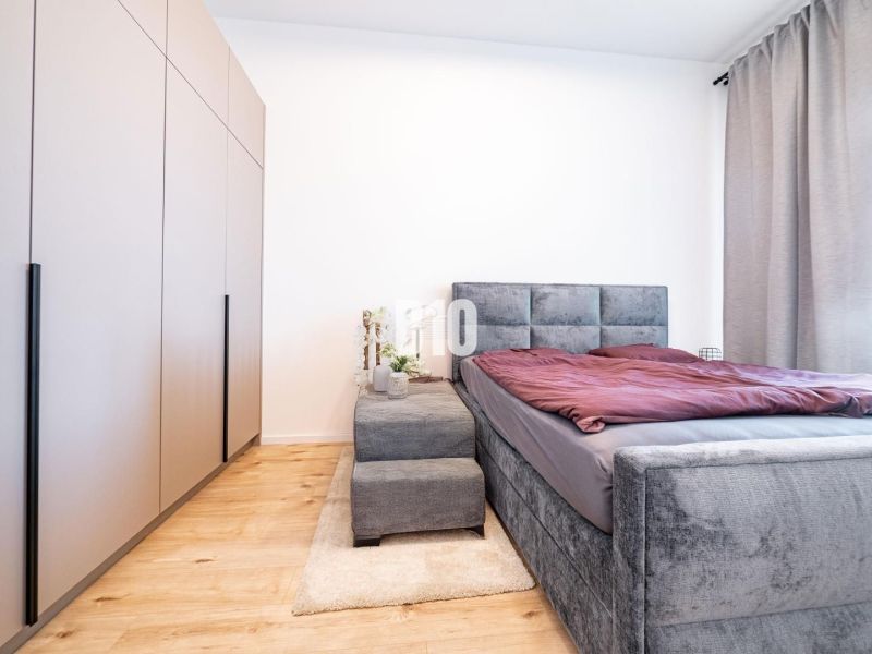 A bedroom in a family house with a bed, wardrobe, and wooden decor flooring.