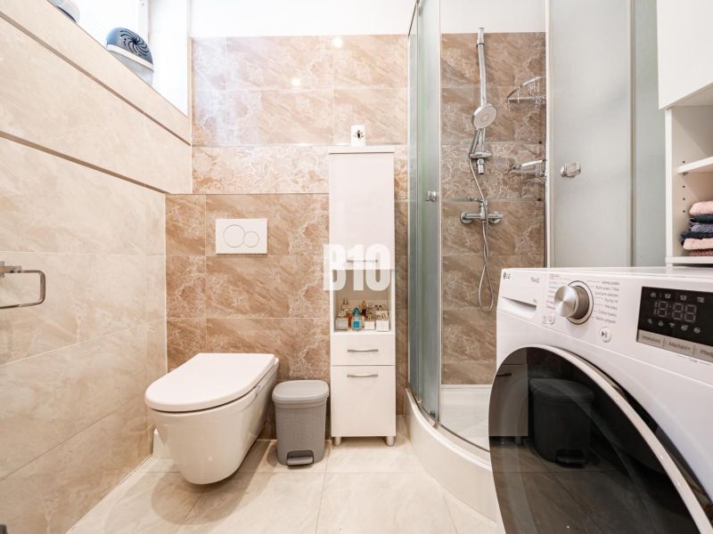 Bathroom in a family house with a washing machine, shower, and toilet.