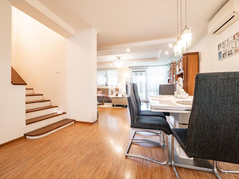 Dining area with wood-patterned flooring and a staircase in a family house.