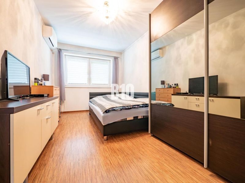 Bedroom in a family house with a wooden decor floor, wardrobe, and television.
