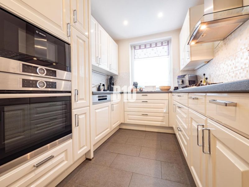 A kitchen with white cabinets and appliances, a wood-decor floor, in a family house.