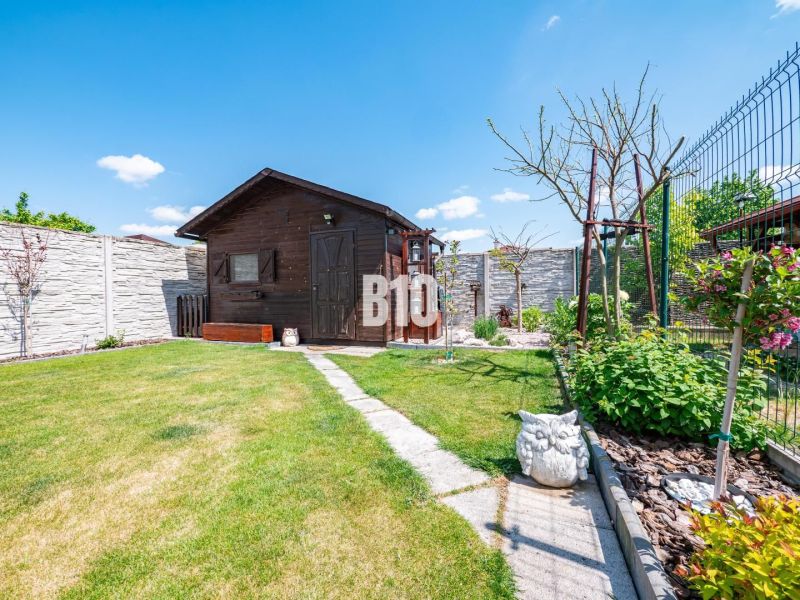 A garden of a family house in Nitra with a garden shed, green lawn, and decorations.