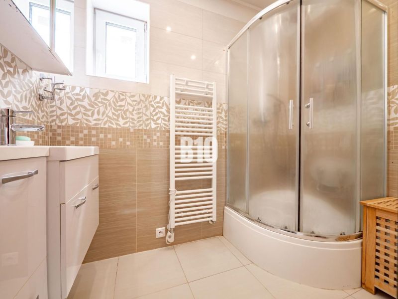 A bathroom in a family house with a corner shower and light tiles.