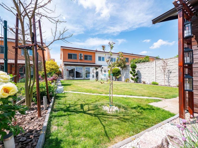 A garden at a family house in Nitra with a lawn, flowers, and a terrace.
